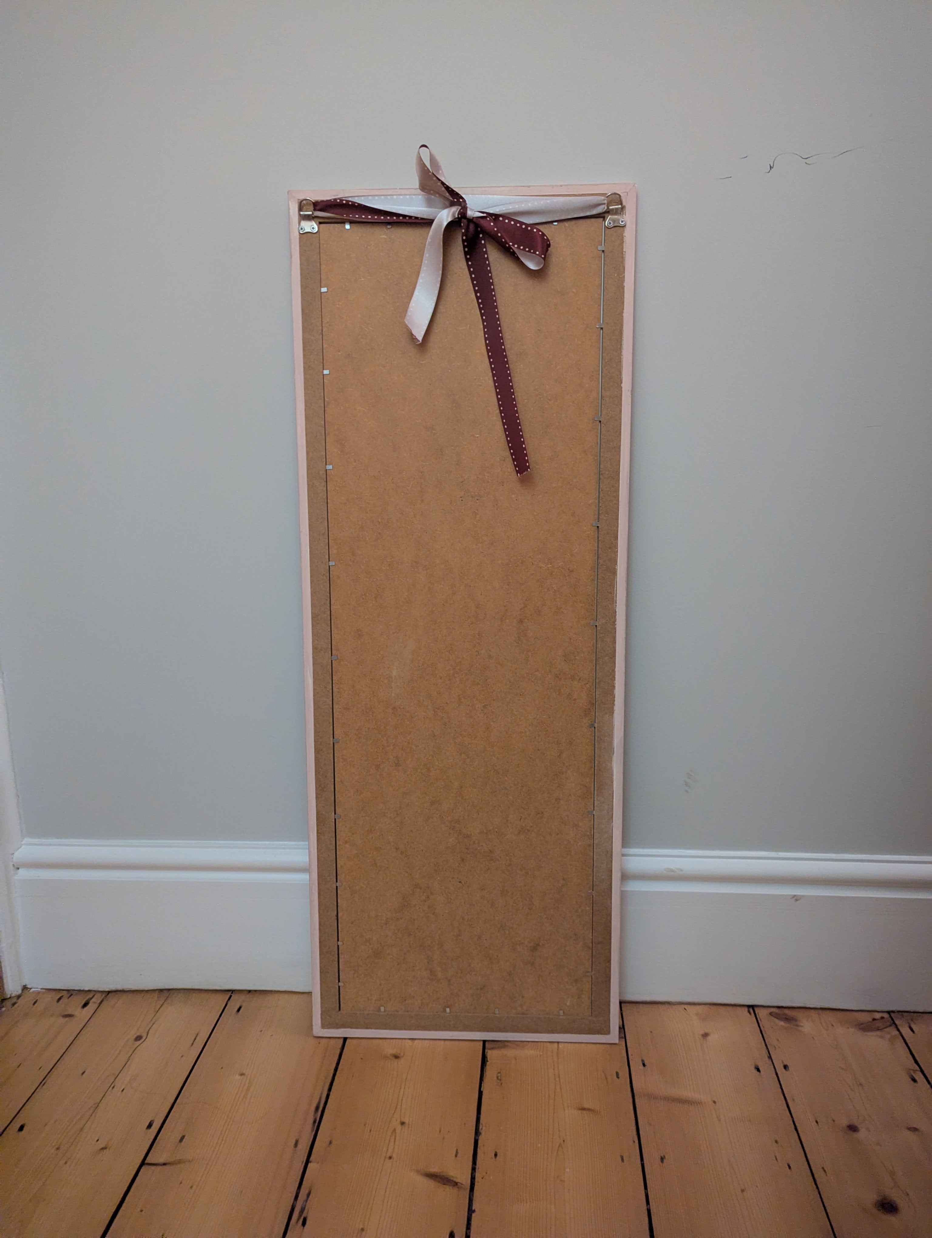 Pale pink mirror with whimsical red and blue pattern.