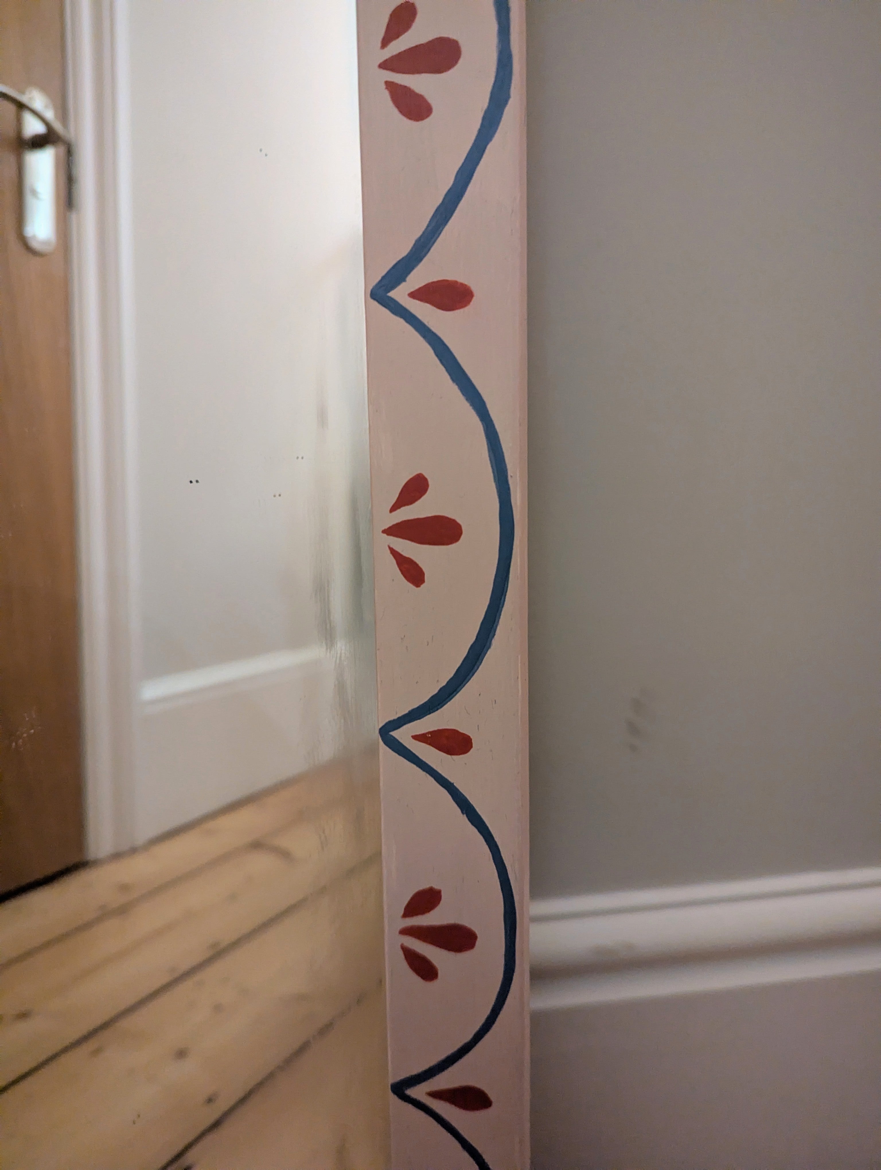 Pale pink mirror with whimsical red and blue pattern.