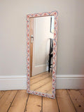 Pale pink mirror with whimsical red and blue pattern.